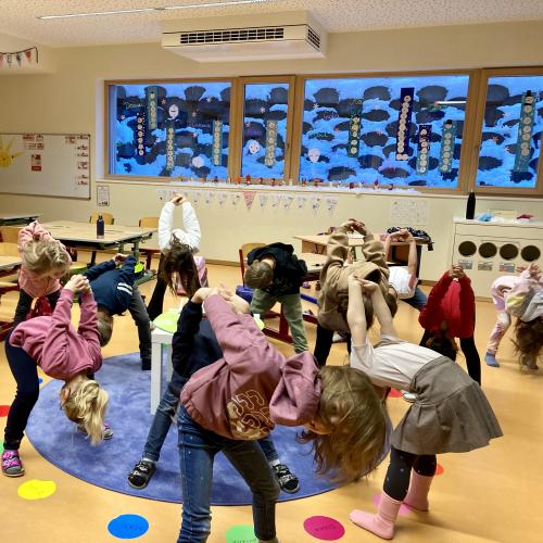 Kinder machen Yoga und drehen ihre Arme hinter dem Rücken nach oben
